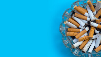 Smoked cigarettes on blue background. Copy space