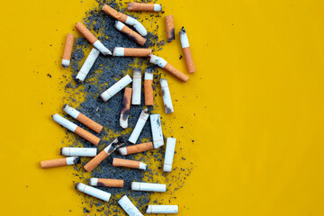 Cigarette butts and ash on yellow background.