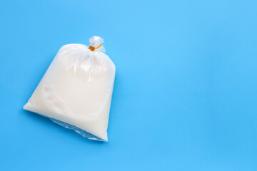 Soymilk in plastic bag on blue background. Top view