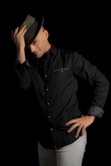 Image of a man with a hat on in the studio. Studio image with a black background.