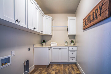 Laundry room interior with cabinets and storage mounted on plain white wall
