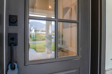 Close up of gray front door of home with glass panels black handle and keyhole