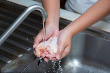 Hand chef washes his hands and cleans the chicken wings at the sink