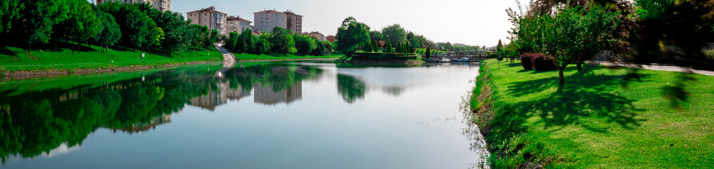 Fototapeta na wymiar Scenic view natural park. Eskisehir, Turkey. The river flowing through the city. Reflections on the water. Long exposure. Panoramic shot. High resolution sharp photo. Panorama banner.