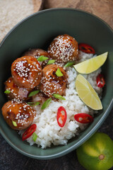 Fried pork meatballs in sweet and sour sauce with rice, high angle view, vertical shot, close-up