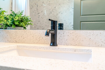 Close up of single white ceramic sink and black faucet of a bathroom vanity