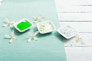 cosmetic creams and white flower, on textile, white painted wooden