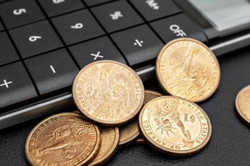 Coins of american dollar and calculator on black. Close up.