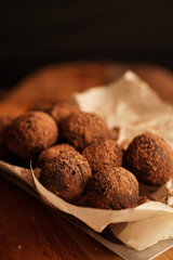 Close-up of chocolate truffles on a wooden plank in dark aesthetic. Keto dessert