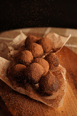 Close-up of chocolate truffles on a wooden plank in dark aesthetic. Keto dessert