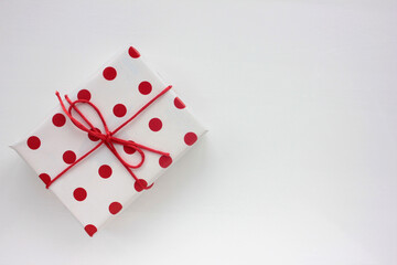 Gift box in red polka dot pattern wrapping paper on a white background. Top view, copy space