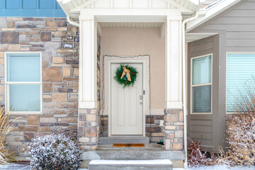 Facade of home with holiday wreath on the front door framed with string lights