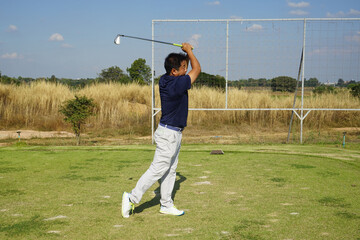 Golfer playing golf in the evening golf course, on sun set evening time. Man playing golf on a golf...