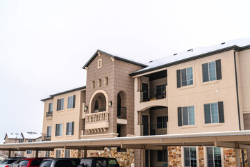 Apartment building with parked vehicles against white sky background in winter