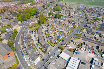 Aerial photo of the village of Morley in Leeds UK, showing an aerial view of the residential street with houses that have solar panels on the roof and a church on the main road on the town