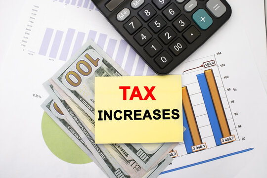 the tax increase is written on a yellow sheet that lies on dollars with documents near the calculator. Concept photo