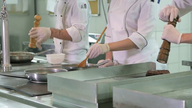 Cooks prepare meals on an electric stove in a professional kitchen in a restaurant or hotel