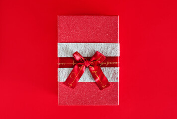 red gift box with a bow on a red background. centered