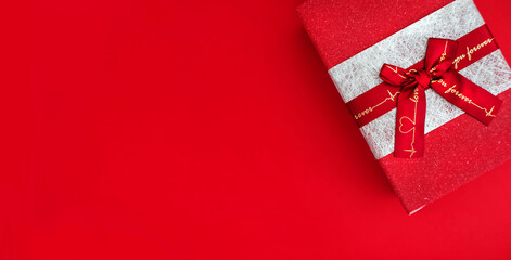 red gift box with a bow on a red background. copy space