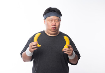 Young Asian funny fat sport man holding banana isolated on white background. Healthy lifestyle concept.