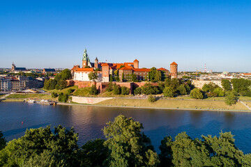 Krakow, Poland. Wawel Hill with royal Cathedral and castle. Aerial view in sunset light. Vistula River.  Riverbanks with tress, promenades parks and  walking people