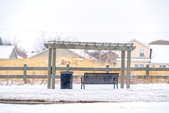 Wooden pergola over a bench that looks out to a frosted neighborhood scenery