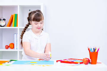 A child with down syndrome sits above a picture of the sun's circle in class at a specialized school