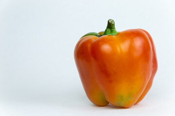 Fresh vegetables, juicy red bell pepper with a green stem stands on an isolated white background. Fresh vegetables side view. Close-up.