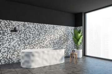 Grey and white bathroom with bathtub and plant on tiled floor, near window