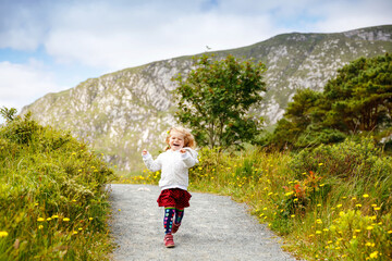 Cute little happy toddler girl running on nature path in Glenveagh national park in Ireland....