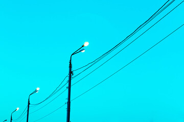Lamp poles with power lines on a background of blue sky. Copy space