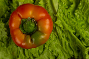 Fresh vegetables, red pepper lies on lettuce leaves on a dark wooden background. Fresh vegetables .