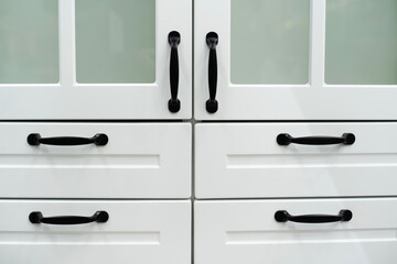 A fragment of a kitchen set in white with black handles. Flat lay. Cropped frame