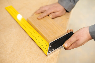 Carpentry works. The process of measuring a board with a ruler to measure angles. Close-up. View from above