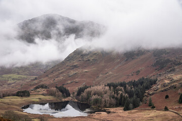 Beautiful landscape Winter sunrise of Blea Tarn from Side Pike in English Lake District with low level clouds over mountain tops