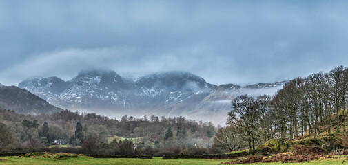 Epic dramatic landscape image of view from Elterwater across towards Langdale Pikes mountain range...