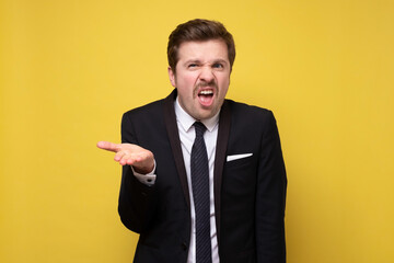 Confused young man spreading hand being in uncomfortable situation.