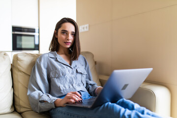 Young smiling woman at home relaxing on the couch with her cat and shopping online