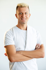 Athletic man portrait. Healthy lifestyle. Sport recreation. Vertical portrait of confident cheerful spa massage therapist in white t-shirt with towel on shoulder isolated on light background.