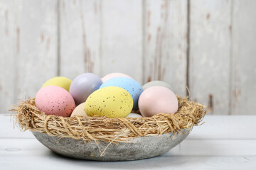Bowl with Easter eggs on wooden table.
