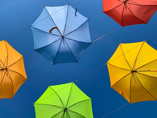 Flying overhead in the sky multicolored open umbrellas. Street art and tourist attraction. Colorful background.