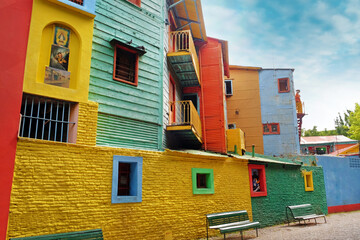 View of colorful buildings in Caminito of the Argentinean district La Boca, in Buenos Aires, with vintage walls against a blue sky.
