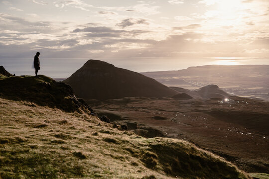 Vista all'alba del quiraing con un ragazzo in balia del vento che ammira il paesaggio