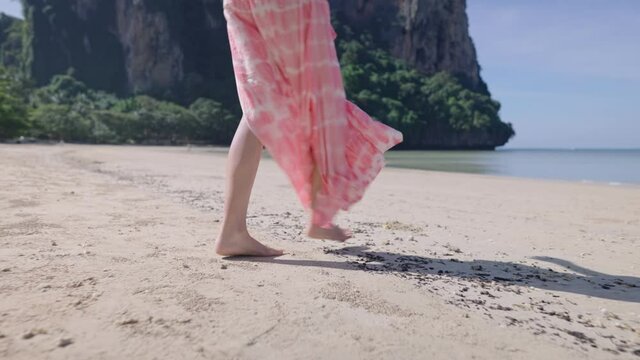 Close up on white slim female legs in long skirt which blown by the wind, strolling by the coast on vacation, amazing natural resources, tourist spending time on relaxing holiday, non urban scene