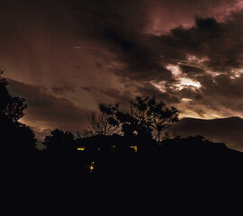 sunset with lightening bolts in the sky snd s as house silhouette 