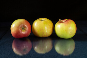 Ripe apple to rest upon table with reflection