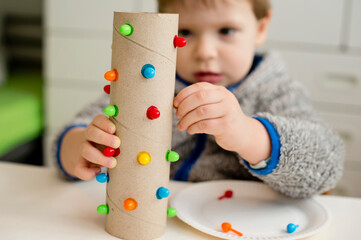 match a color. insert correct color pin to assigned hole. Concentrated baby face, working on new task.Toddler hands on paper tube. fine motoric skills, Montessori, ergotherapy, DIY