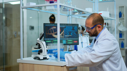 Biologist doctor checking DNA samples in modern equipped laboratory. Multiethnic team examining vaccine evolution in medical lab using high tech and chemistry tools for scientific research.