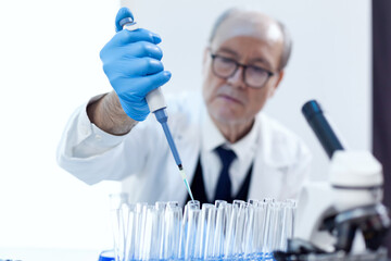 Chemist scientist working with dropper pipette and blue substance in modern laboratory. Senior...