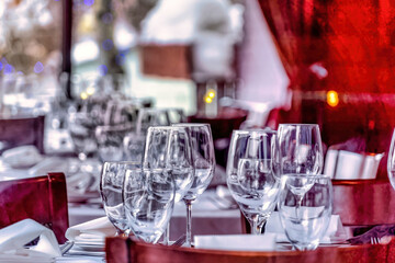 Wine glasses on round dining table with white cloth cover and brown wood chairs